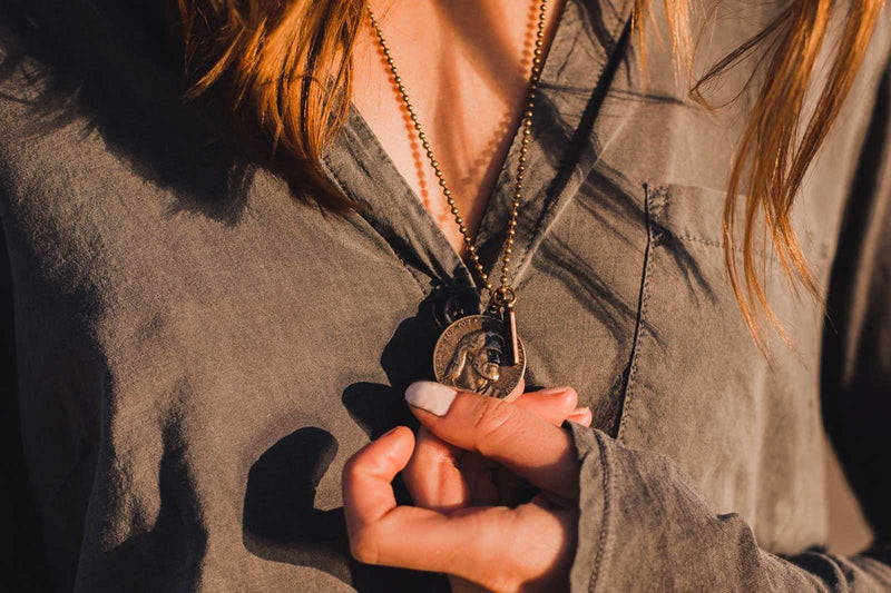 Close up of a woman wearing a bronze tone vintage inspired Let Go Let God Jesus round pendant on a bead ball chain