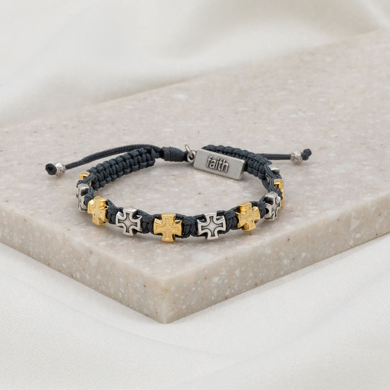 slate woven bracelet with alternating silver and gold tone medals and a silver charm tag at the slip knot closure with the word faith