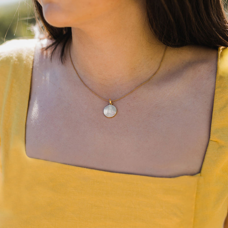 Mother of Pearl Mother Mary Necklace necklace on a young woman with dark brown hair wearing a yellow square neck top