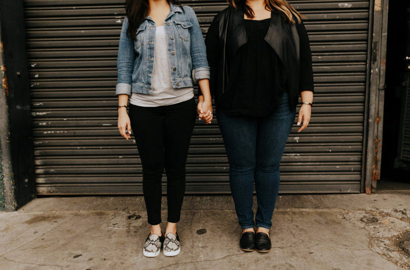 2 women wearing casual clothes standing in front of loading dock door clasped hands 