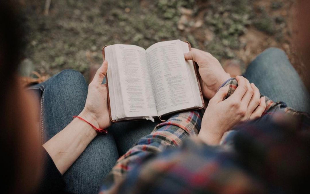 seated man and woman holding open book together