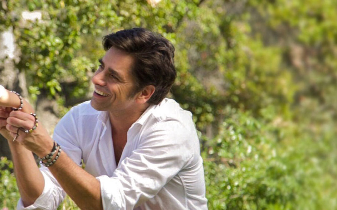 John Stamos wearing and holding hand wearing St. Amos Love Bracelet