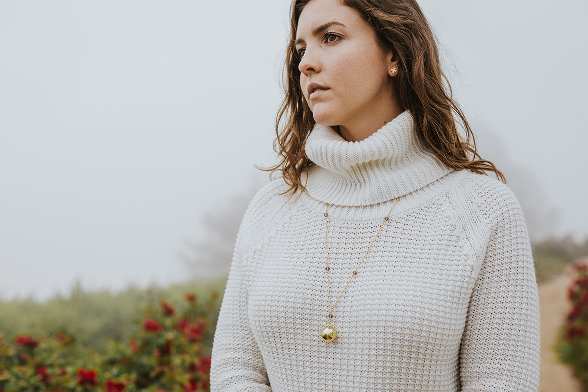 young woman in white sweater in field on foggy day