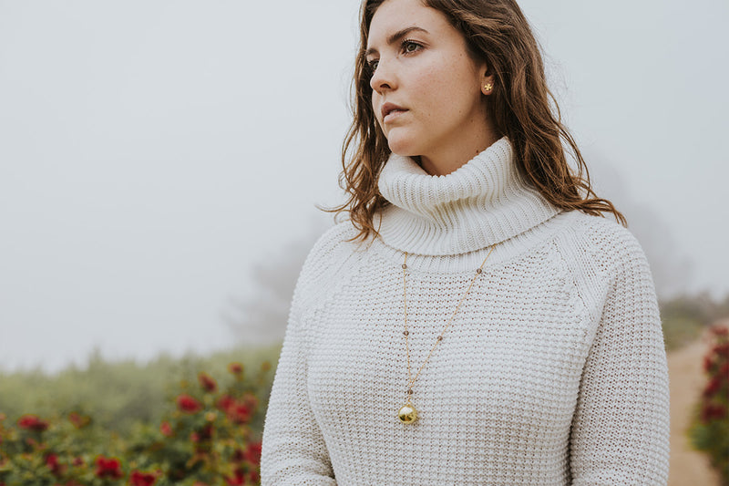 young woman in white sweater in field on foggy day