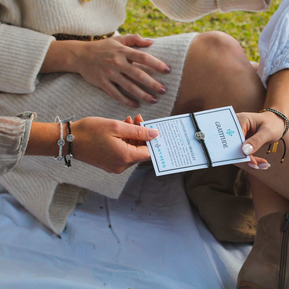 friends on picnic blanket sharing gratitude bracelets on inspirational cards