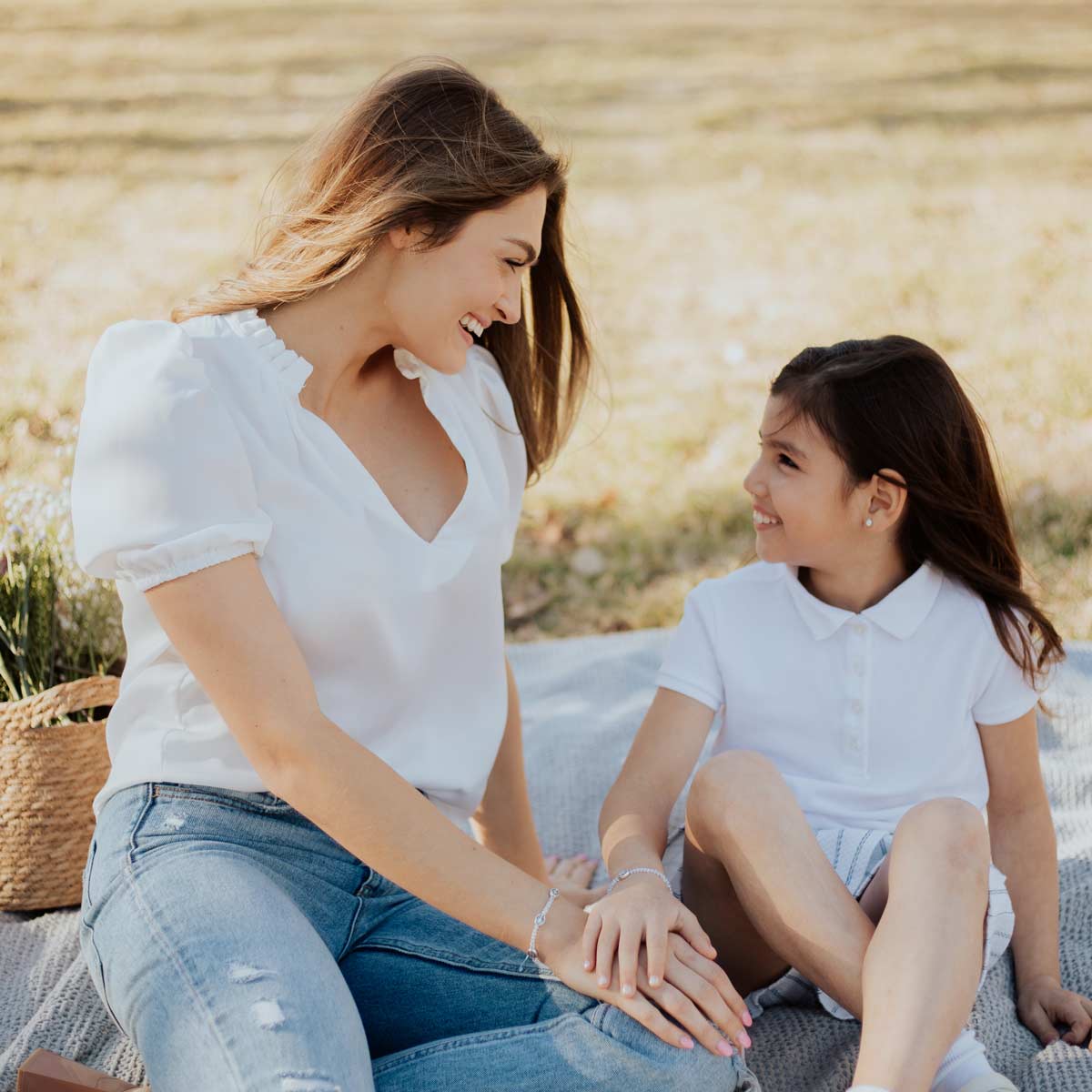 young mother and daughter in a field with a basket of flowers