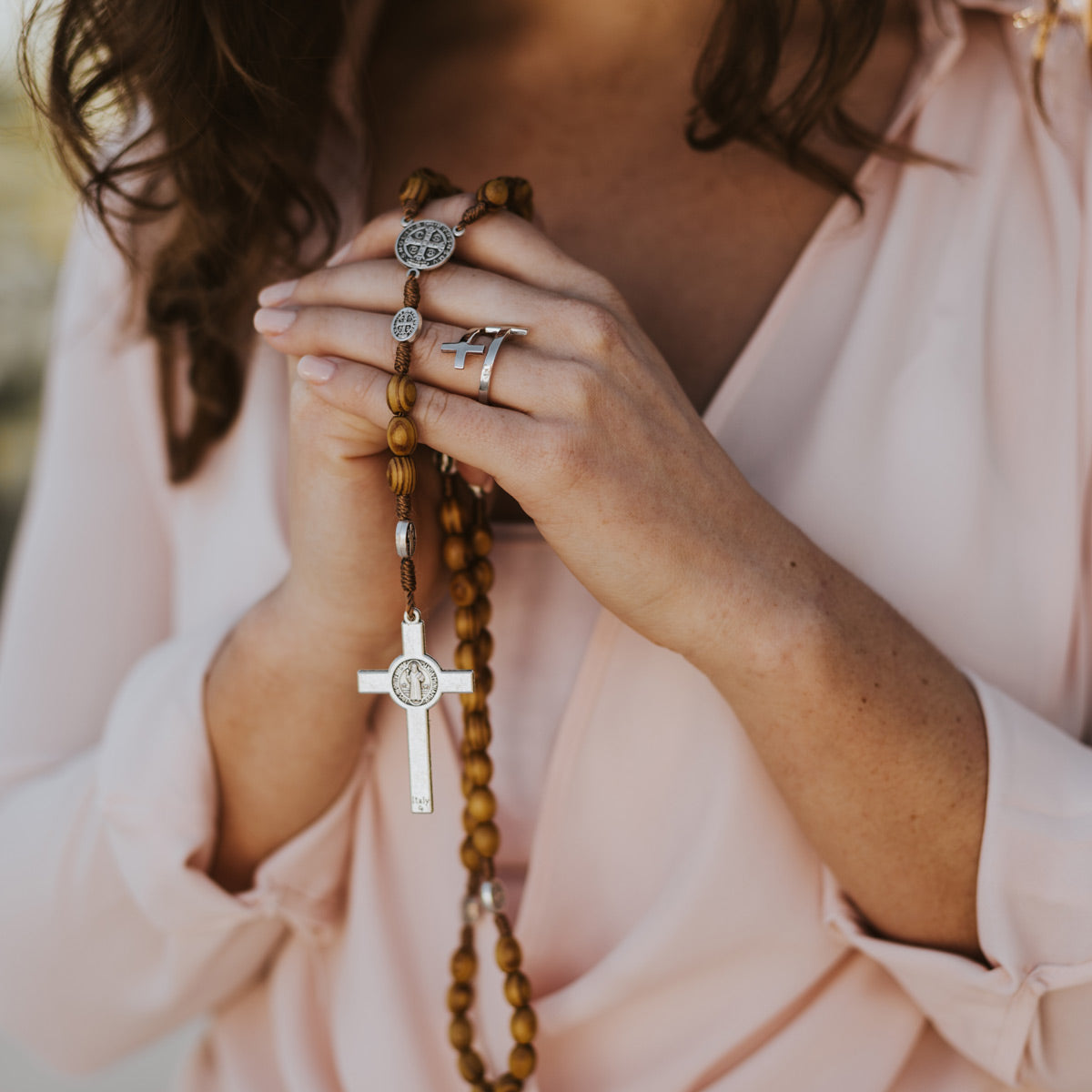 a woman holding an olive wood rosary