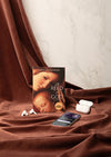 Book titled 'The Reed of God' by Caryl Phillips on a brown fabric background with a phone and earbuds.