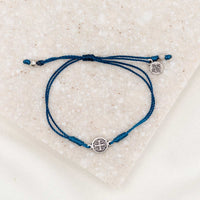 silver-tone St. Benedict medal on denim blue bracelet cording with a slipknot closure