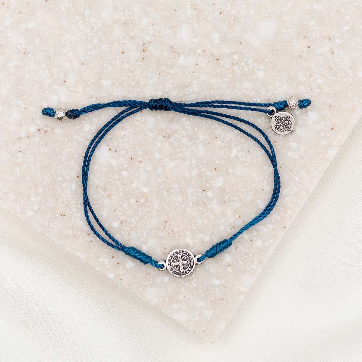 silver-tone St. Benedict medal on denim blue bracelet cording with a slipknot closure