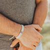 Man wearing Blessing for a Cure for Him tan woven Benedictine Bracelet  with silver tone St. Benedict Medal