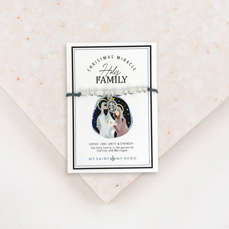 Adjustable slate grey bracelet cording with a silver-tone metal bead and a Holy Family medal, presented on a card with the text 'Christmas Miracle Holy Family.'.