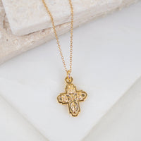 close up of Gold-tone four-way cross pendant on gold chain
