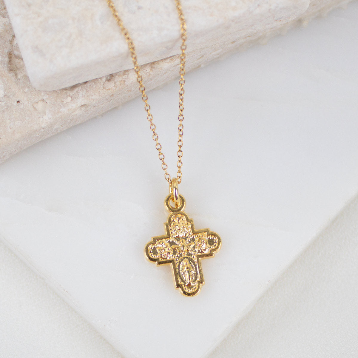 close up of Gold-tone four-way cross pendant on gold chain