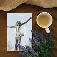 A Day Prayer Planner booklet featuring a crucifix statue cover, styled in a flat lay with a cup of coffee, lavender flowers, and burlap on a brown surface.