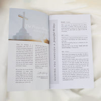 An open 40 Day Prayer Pledge booklet showing the left-hand page with a printed prayer header and text, and the right-hand page with a short devotional reading titled 'Guiding You Through a Powerful 40 Days.' 
