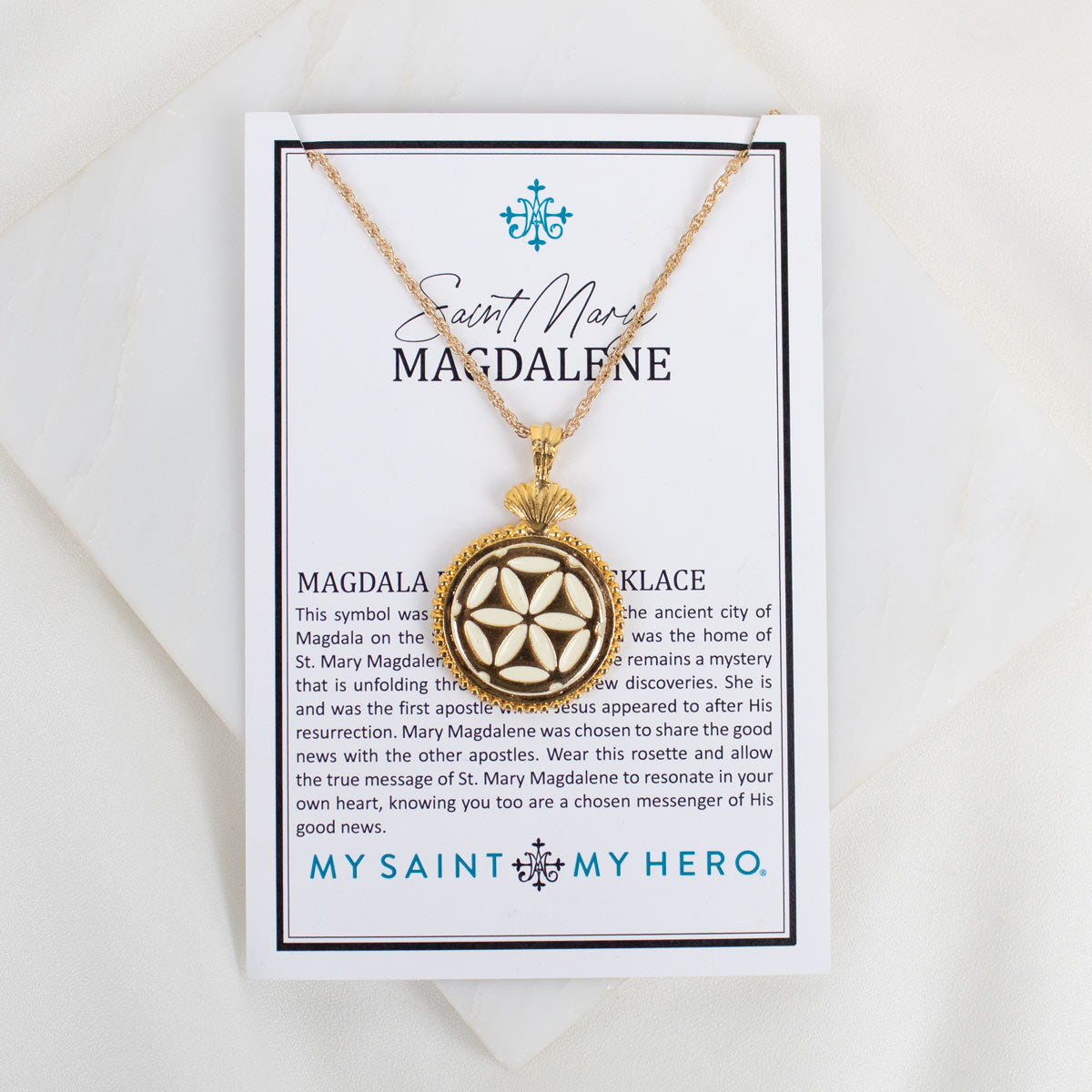 Gold necklace with pendant on a card featuring 'My Saint My Hero' branding