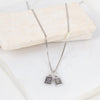 Silver necklace with two pendant charms on a white surface