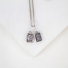 Silver necklace with two book-shaped sterling silver sacred heart scapular pendants on a white background