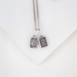 Silver necklace with two book-shaped sterling silver sacred heart scapular pendants on a white background