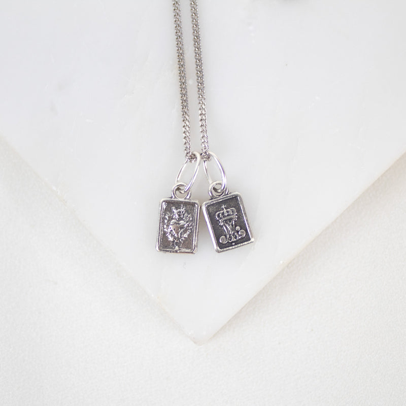 Silver necklace with two book-shaped sterling silver sacred heart scapular pendants on a white background