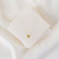 Heart-shaped pendant necklace on a white cushion against a light background