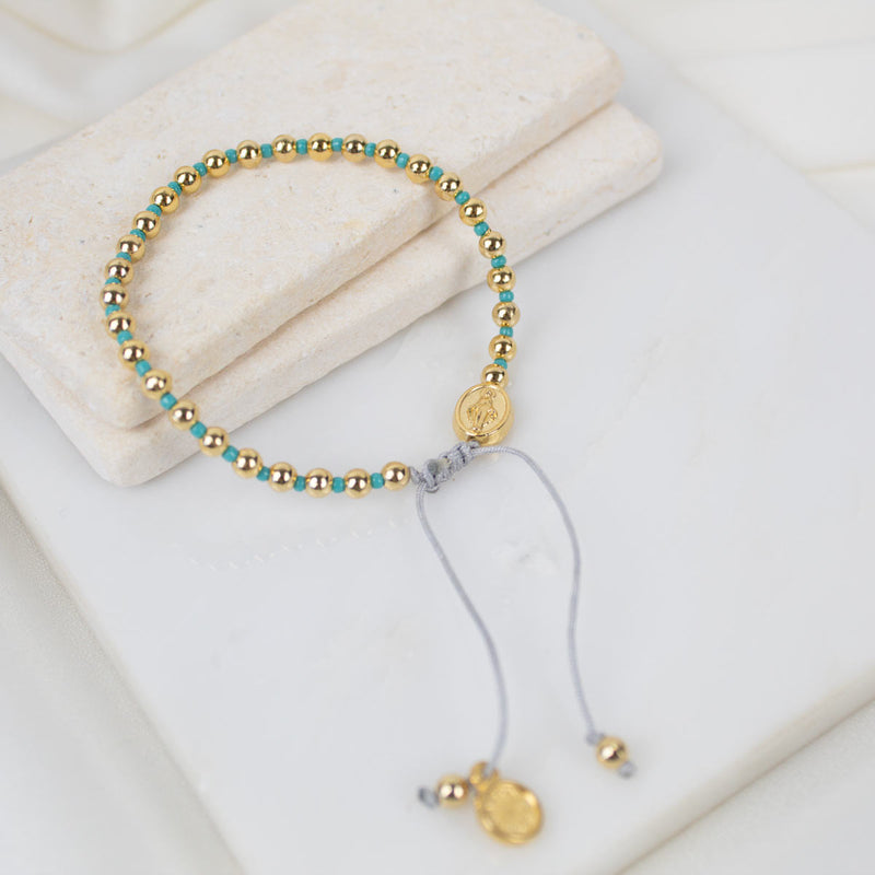 Bracelet with gold and turquoise beads on a white surface