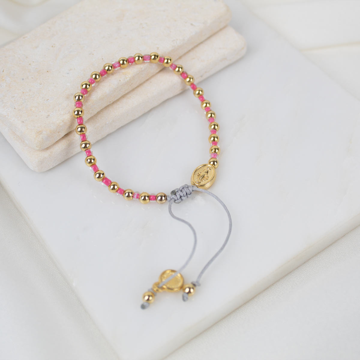 Bracelet with pink and gold beads on a white surface