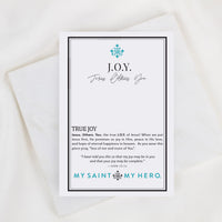 A printed card with a black border and teal text reading 'JOY. Jesus Others.