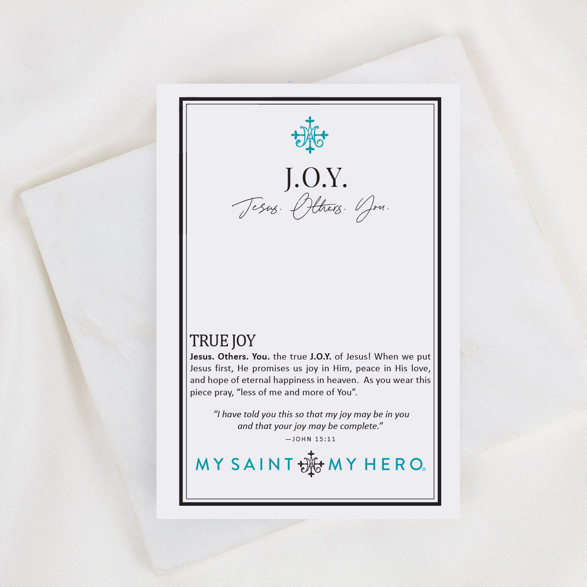 A printed card with a black border and teal text reading 'JOY. Jesus Others.
