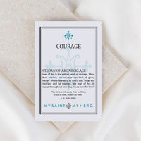Card with text about St. Joan of Arc necklace on a textured surface