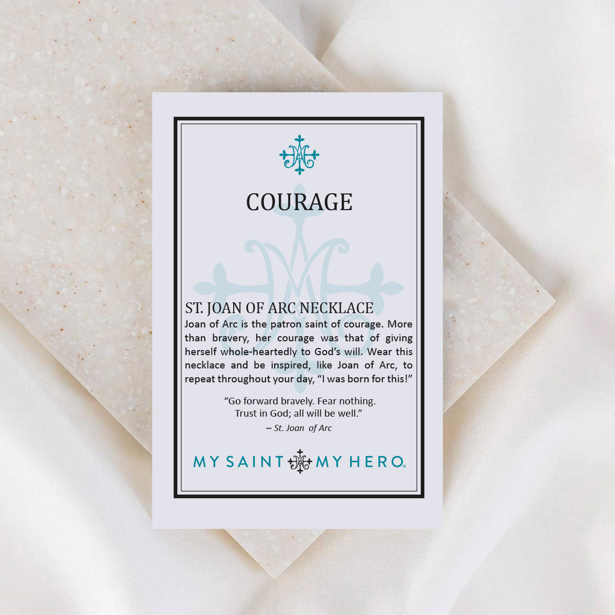 Card with text about St. Joan of Arc necklace on a textured surface