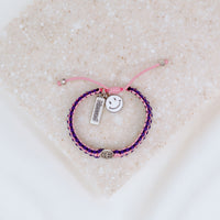 Kids Benedictine pink purple thread handwoven blessing bracelet with silver tone blessed charm and white enamel happy face