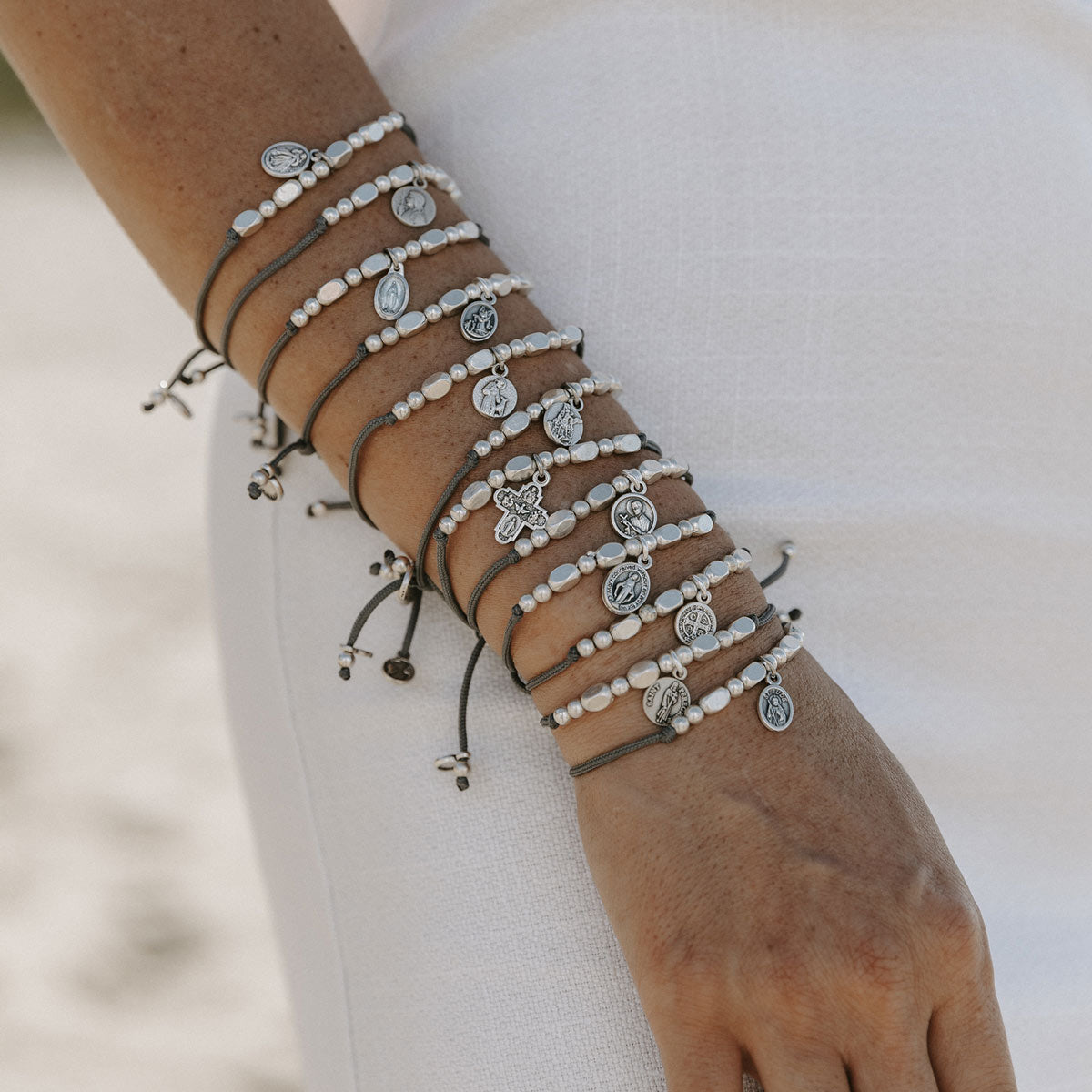 Multiple bracelets with beads and small charms on a wrist against a neutral background