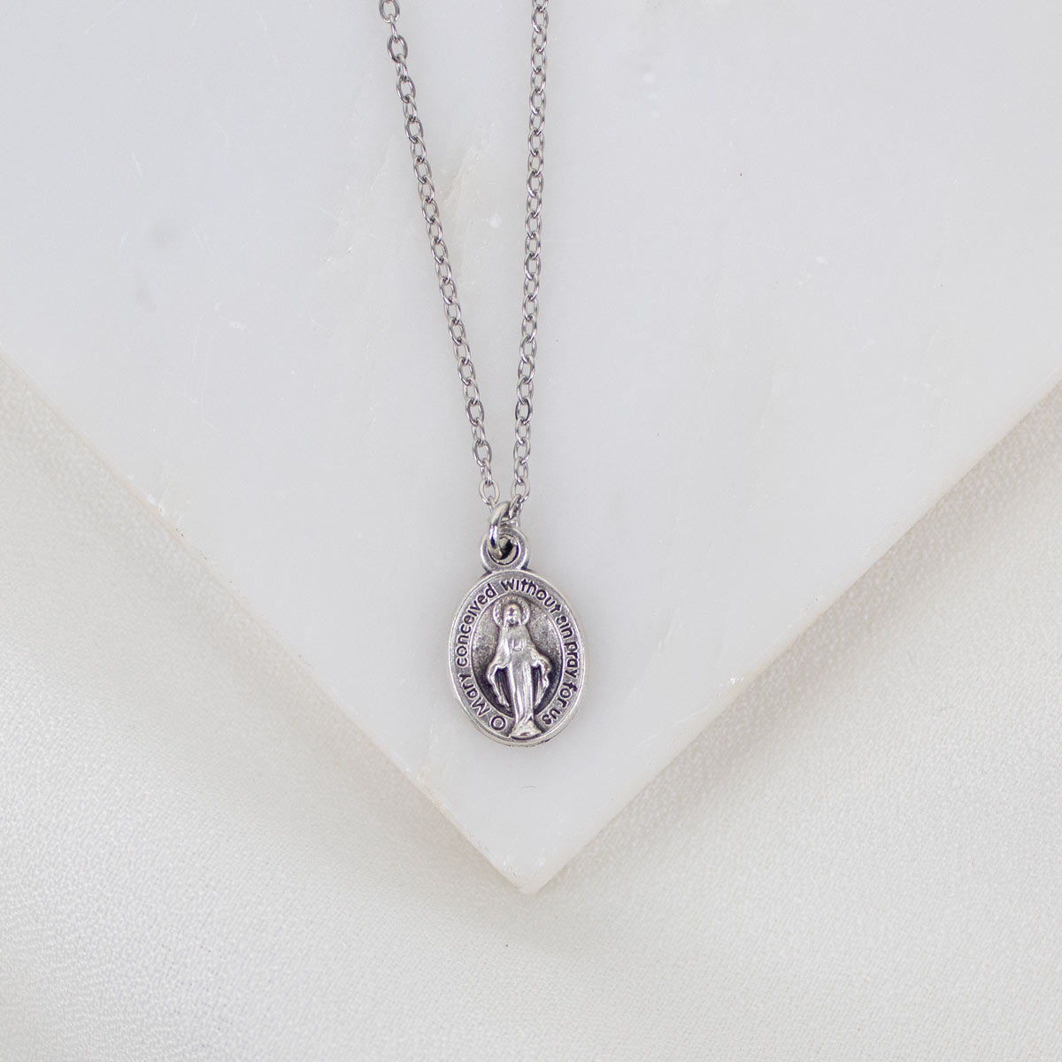 Silver Miraculous Medal necklace with a pendant on a white background