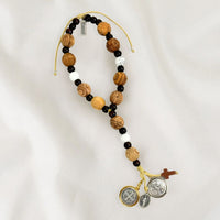 A door hanger made of hand-carved olive wood, featuring a two-tone Benedictine medal, a howlite cross, and silver-tone Miraculous Mary and Archangel Michael medals.