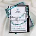 Rosary Wrap Bracelet with white, blue, and gray crystals and silver tone crucifix, Miraculous Mary medal and Benedictine medal in a gifting box