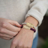 Person wearing a bracelet with gold angel wing charms on a blurred background