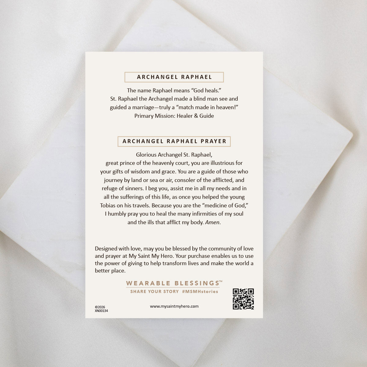 An inspirational product information card for the Archangel Raphael Guardian Angel Necklace, placed on a white marble background. The card reads "ARCHANGEL RAPHAEL" at the top, explaining that the name means "God heals," followed by the "ARCHANGEL RAPHAEL PRAYER" asking for guidance, healing, and protection. At the bottom, a "WEARABLE BLESSINGS" brand logo and a QR code are visible.
