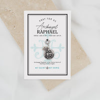 A silver-toned religious charm featuring a circular medallion with an embossed depiction of two figures, alongside a small heart-shaped charm, suspended from a lobster clasp on a light gray background.