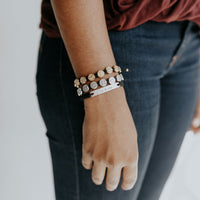 close up of a woman's arm wearing a black woven Be the One Bracelet with two Benedictine Blessing Bracelets