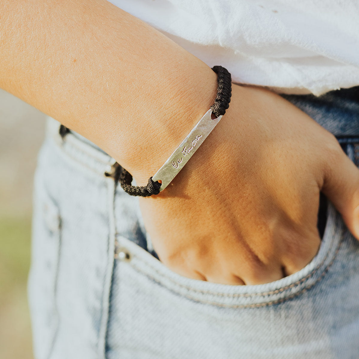 close up of a person wearing a black woven Mother Teresa Be the One Blessing Bracelet