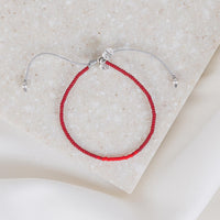 overhead photo of the red seed bead slipknot caitlin and john stamos human trafficking awareness bracelet