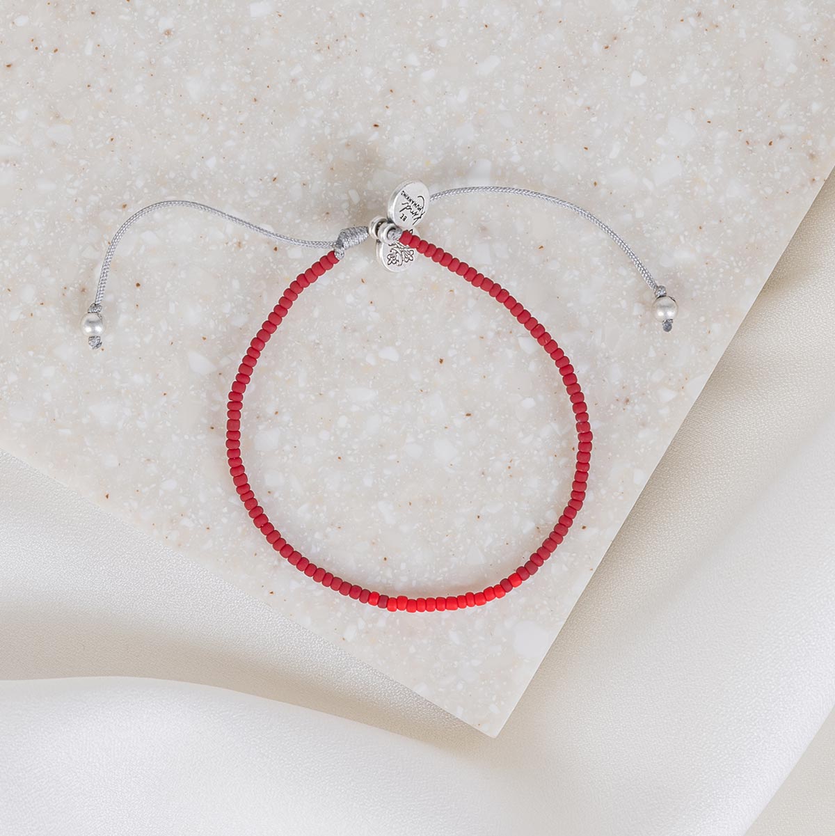 overhead photo of the red seed bead slipknot caitlin and john stamos human trafficking awareness bracelet