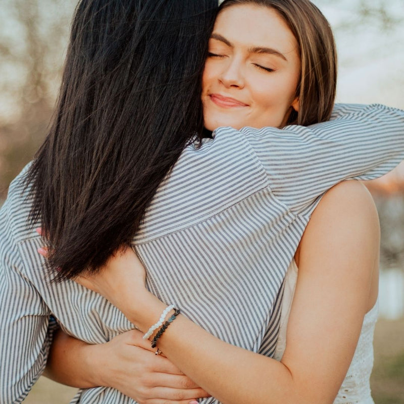 two women hugging one wearing both Belonging Heart Upon Heart Bracelets - Giving Back to Suicide Prevention