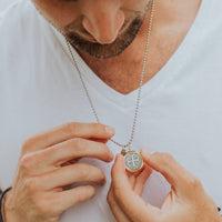 Man holding the large 23mm Benedictine Medal necklace with a pendant against a white background