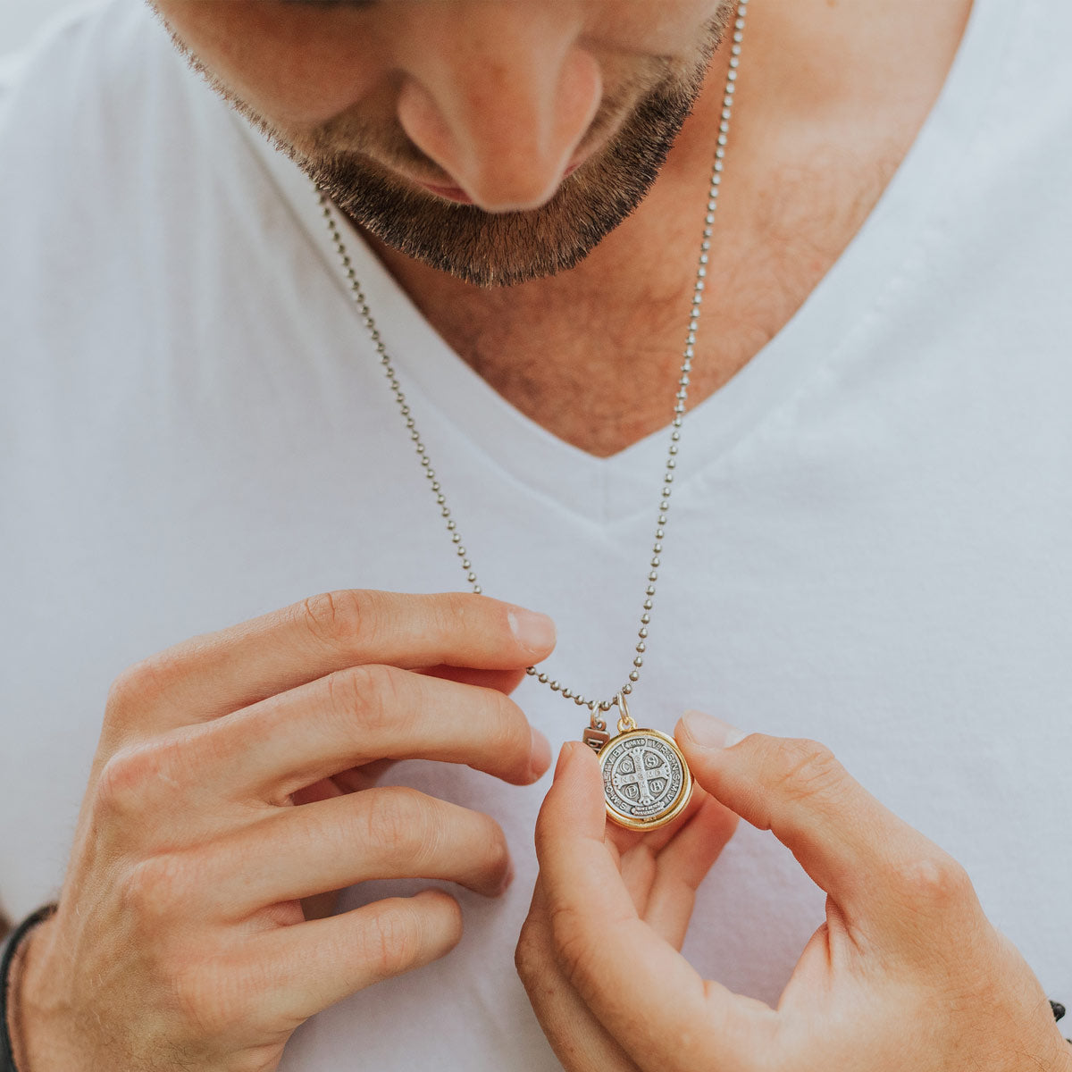Man holding the large 23mm Benedictine Medal necklace with a pendant against a white background