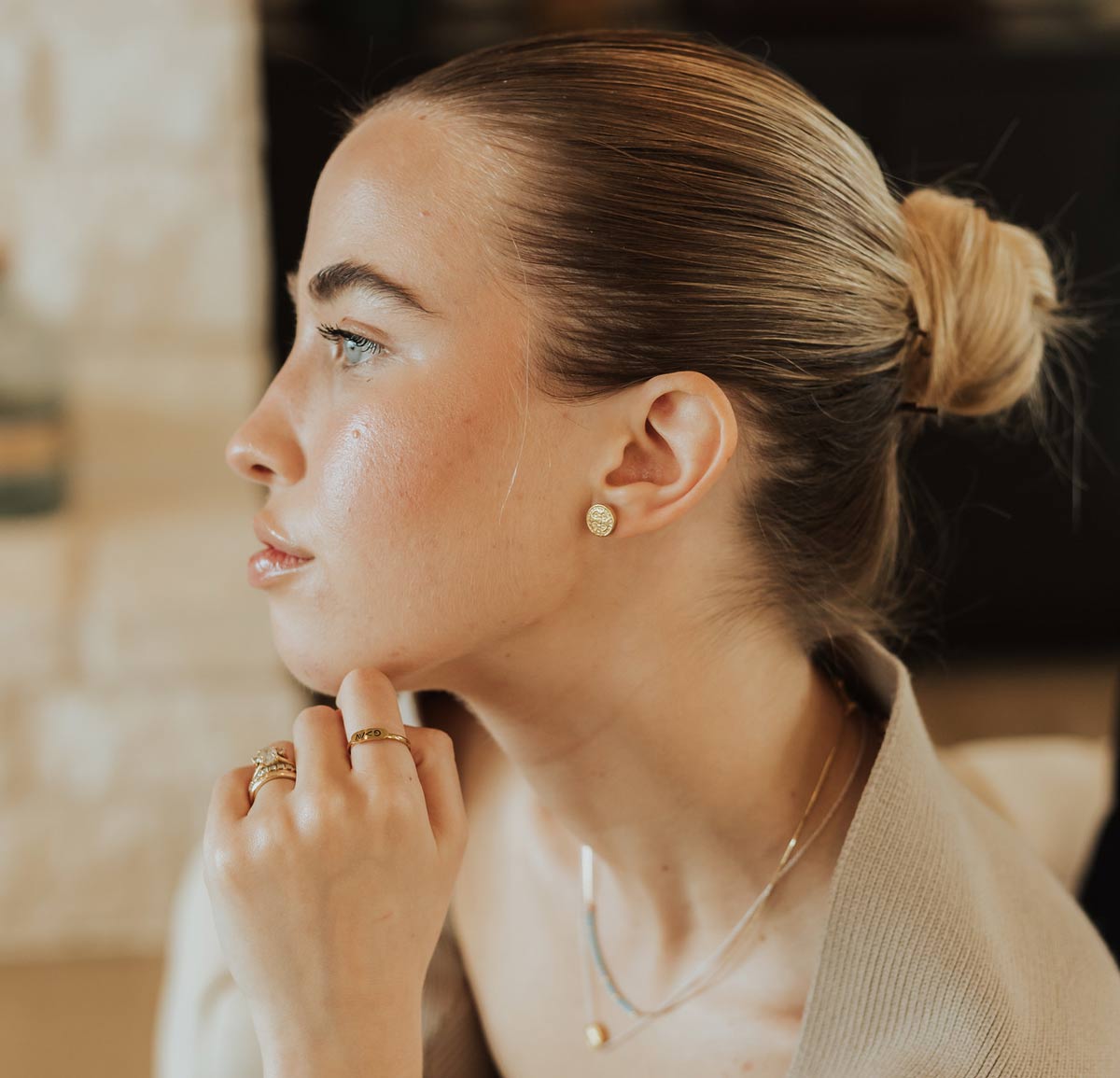 Woman wearing My Saint My Hero gold Benedictine stud earrings and layered faith jewelry.
