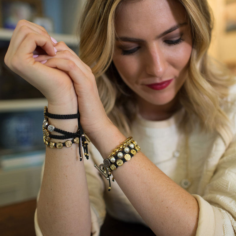 Woman wearing multiple bracelets on her wrist, with a blurred indoor background