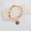 Beaded bracelet with a silver charm on a white stone surface
